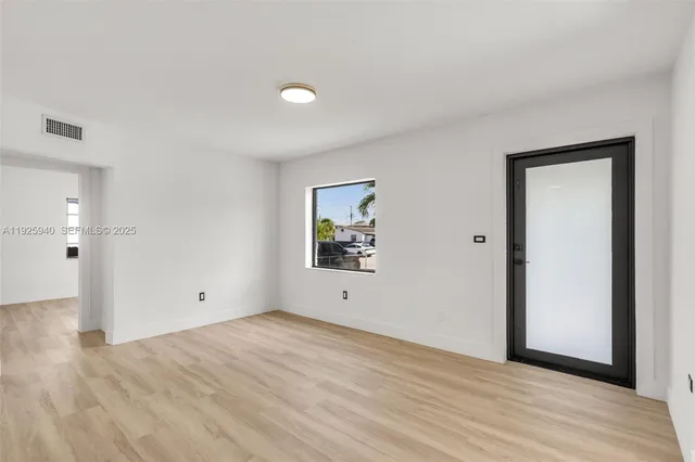 a view of an empty room with wooden floor and closet