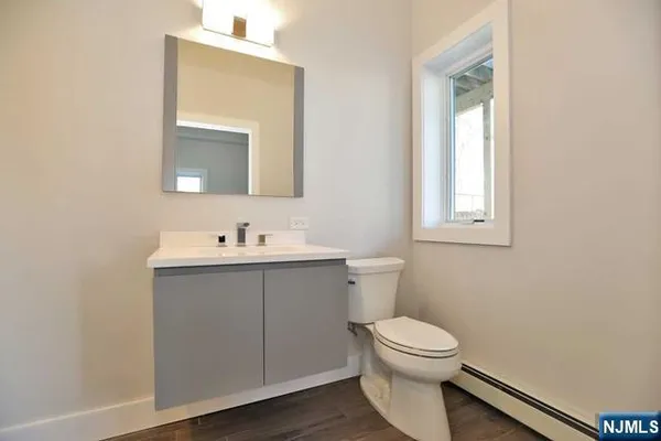 a bathroom with a toilet a sink a mirror and a window