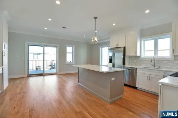 a large kitchen with stainless steel appliances granite countertop a sink a window and wooden floors
