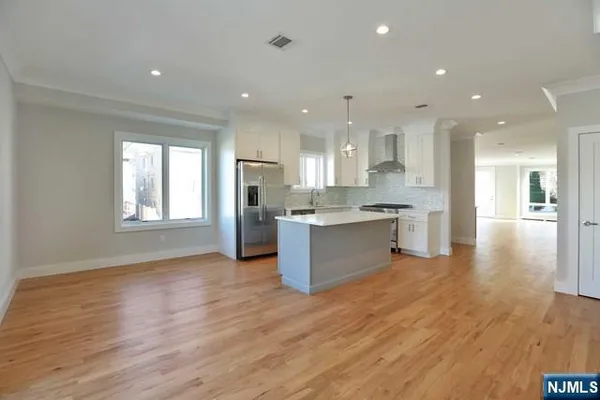 a large kitchen with stainless steel appliances granite countertop a large counter top a sink and a refrigerator