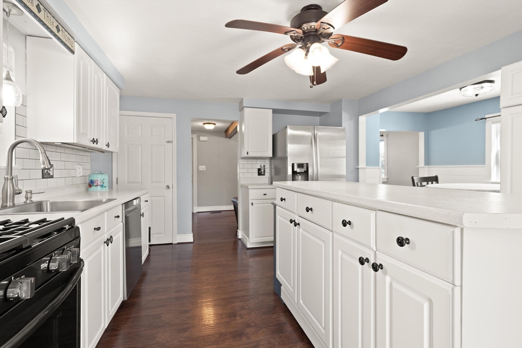 19 Cherry Street Hudson, MA 01749 - Photo 12 of 28 a large white kitchen with a stove top oven a sink a refrigerator and a chandelier