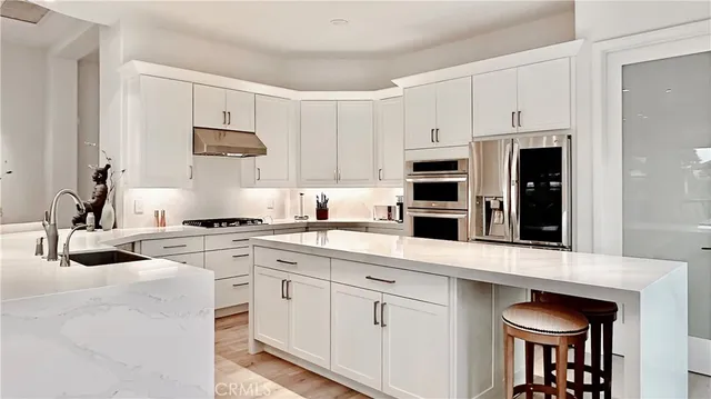a kitchen with stainless steel appliances granite countertop a stove a sink and white cabinets