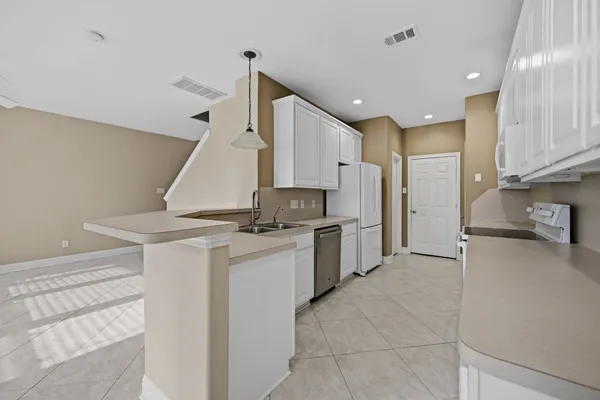 a kitchen with stainless steel appliances granite countertop a sink and dishwasher a refrigerator with white cabinets