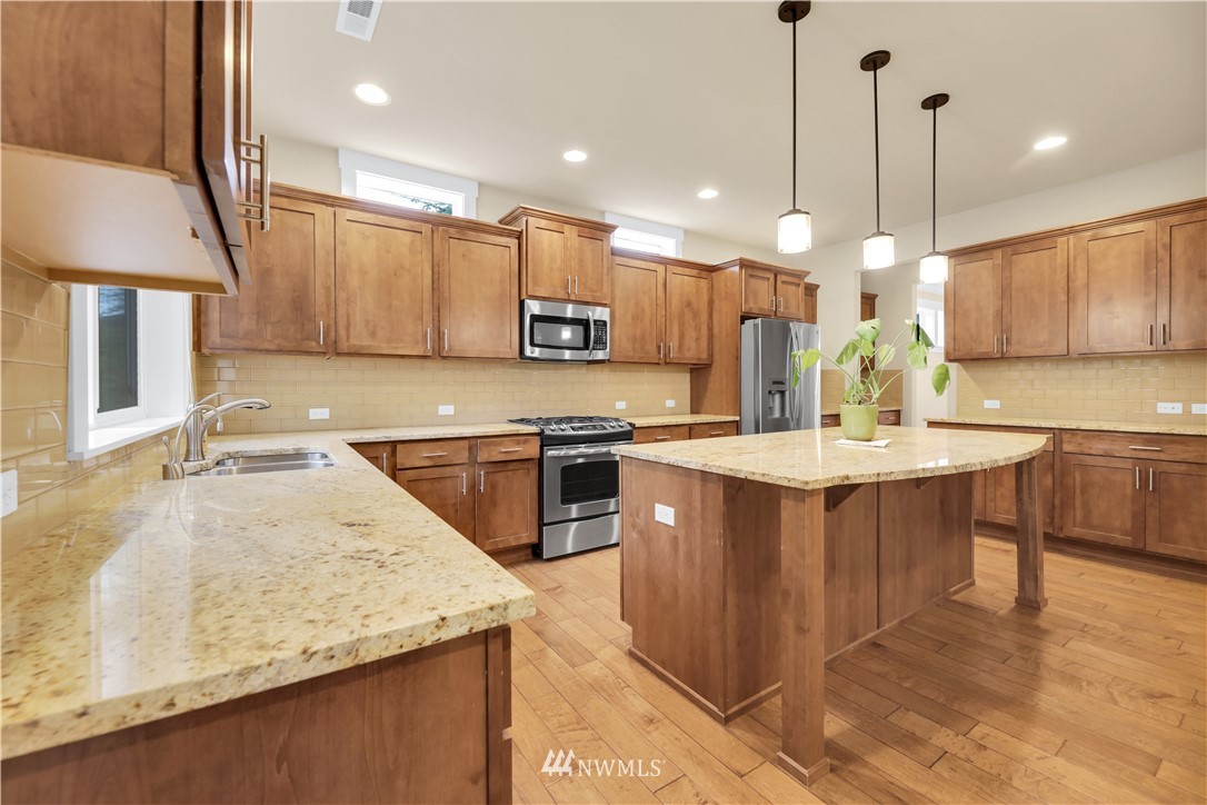 6117 Northeast 1st Street Renton, WA 98059 - Photo 9 of 39 a kitchen with stainless steel appliances granite countertop a sink a stove and a wooden floors