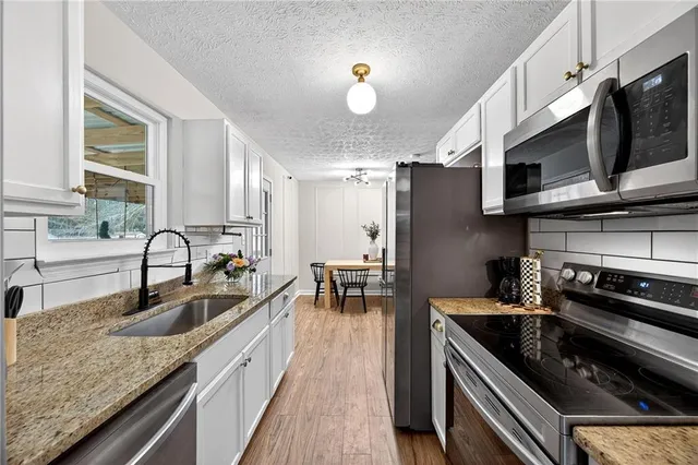 a kitchen with stainless steel appliances granite countertop a sink stove and microwave