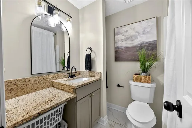 a bathroom with a granite countertop sink mirror vanity and toilet
