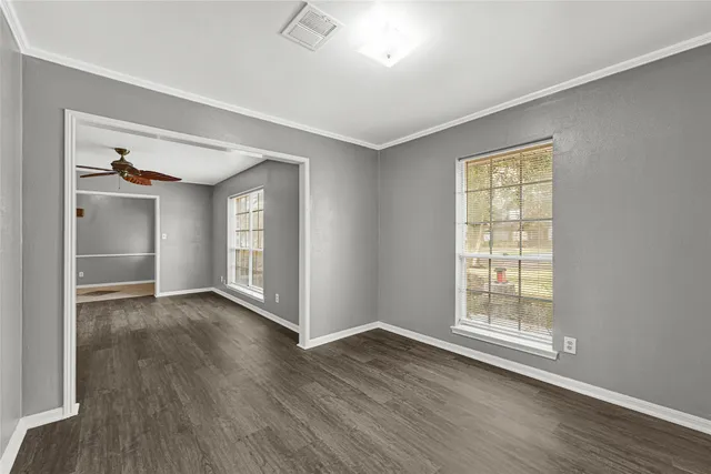 an empty room with wooden floor and windows