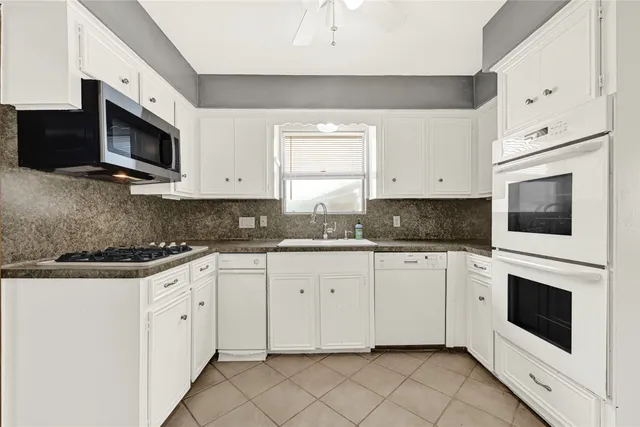 a kitchen with stainless steel appliances granite countertop white cabinets a sink and dishwasher