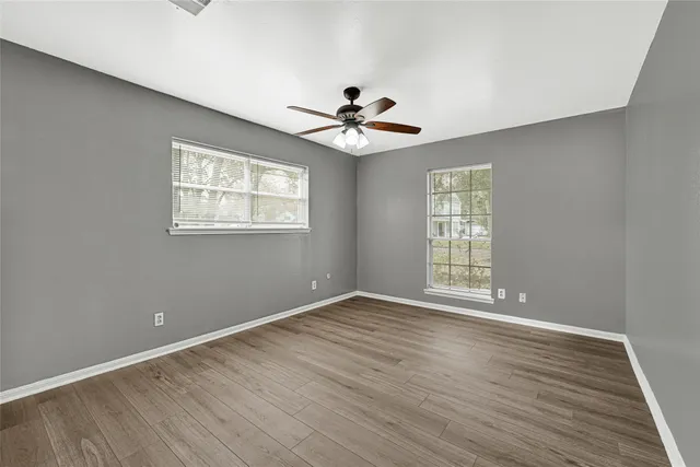 a view of an empty room with a window and wooden floor