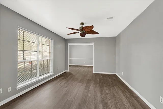 a view of empty room with wooden floor and fan