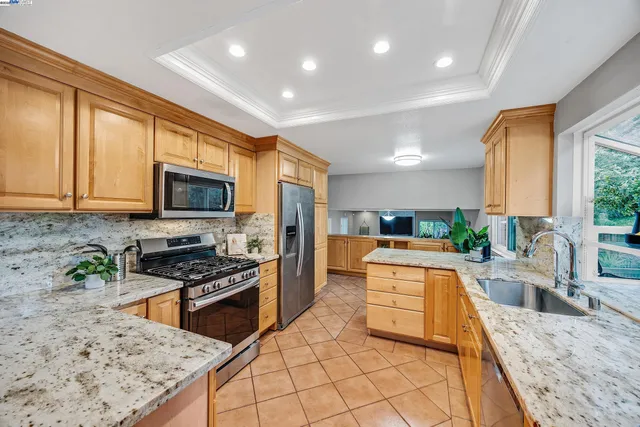 a large kitchen with stainless steel appliances granite countertop a stove top oven a sink a dining table and chairs