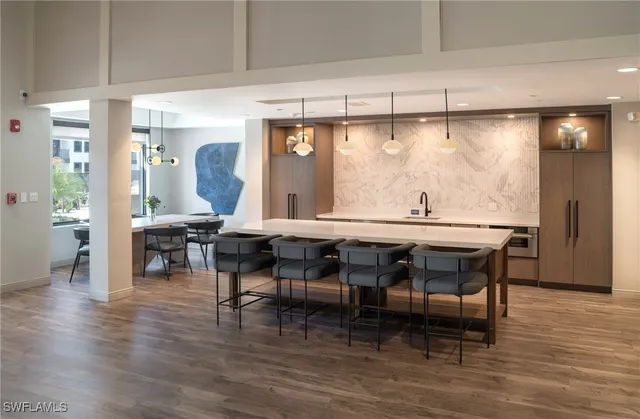 a dining hall with stainless steel appliances granite countertop a table chairs and a wooden floor