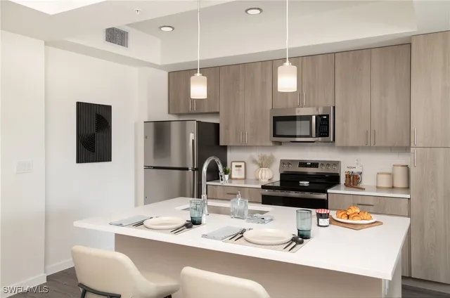 a kitchen with stainless steel appliances granite countertop a sink a stove a microwave a refrigerator and white cabinets