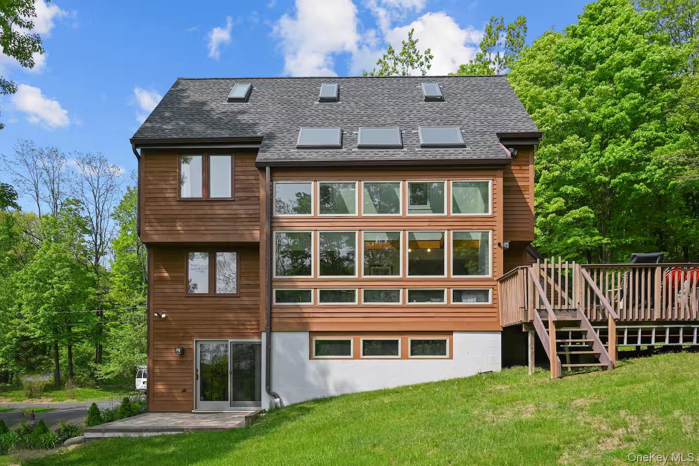 Rear view of house with a deck, a yard, and a shingled roof