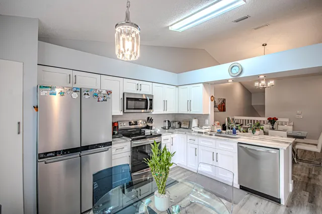 a room with lots of white furniture and chandelier