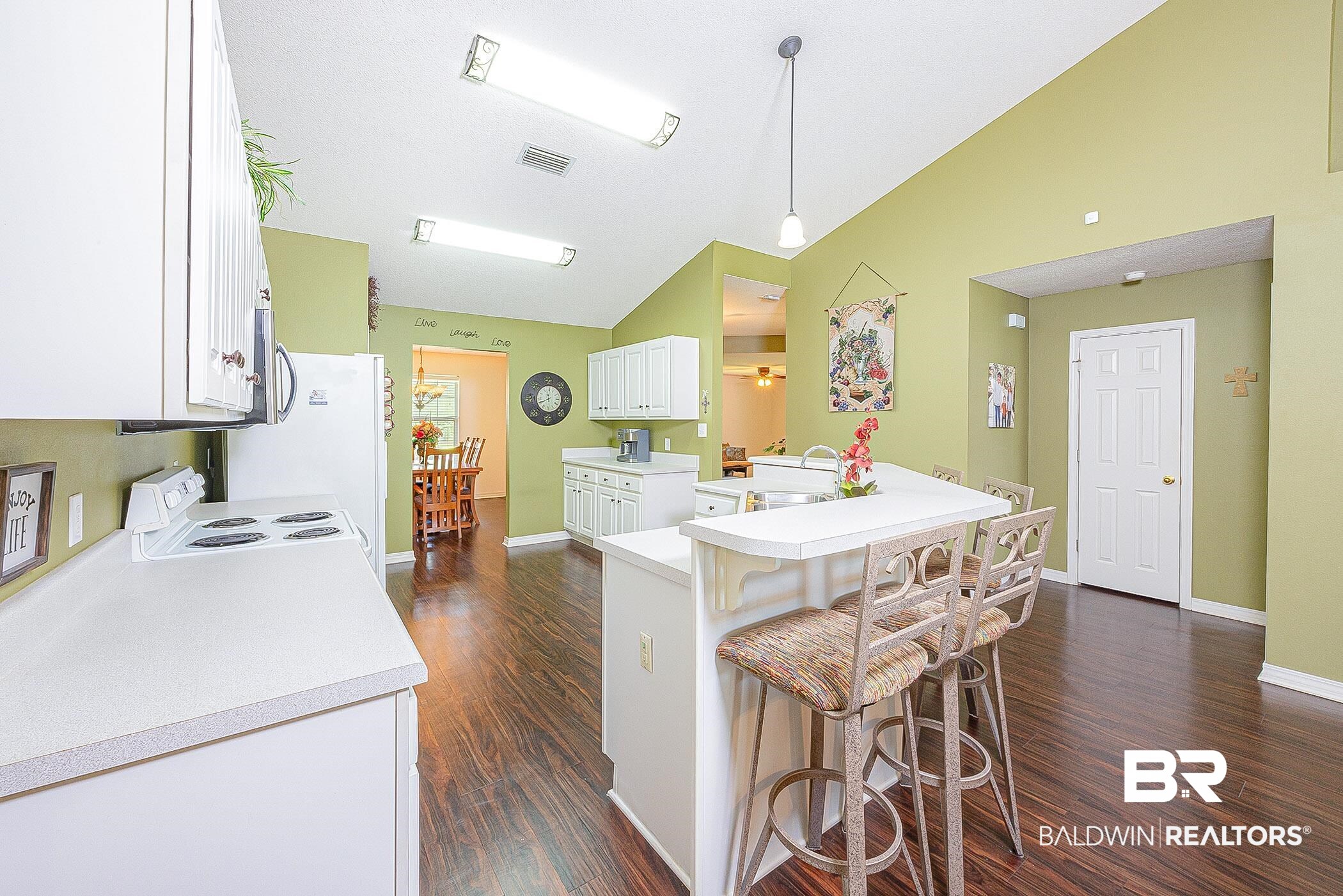 16154 Parke Boulevard Foley, AL 36535 - Photo 12 of 44 Kitchen with a breakfast bar area, white cabinetry, white range with electric stovetop, dark hardwood / wood-style floors, and vaulted ceiling