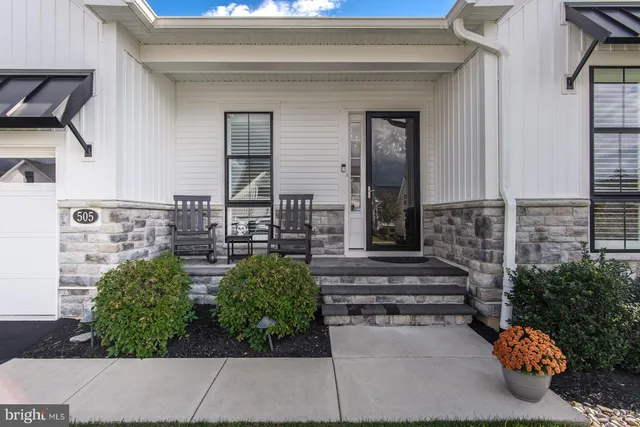 a living room with furniture kitchen view and a wooden floor