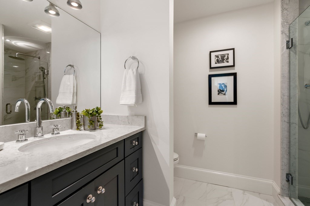 24 Maxfield Street Boston, MA 02132 - Photo 26 of 36 a bathroom with a double vanity sink a mirror and a bathtub