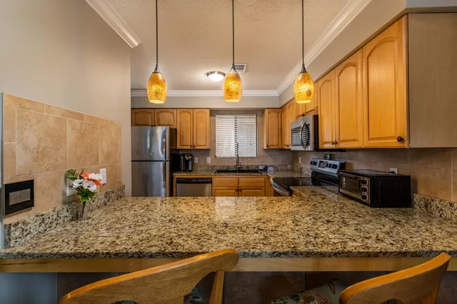 a living room with stainless steel appliances granite countertop furniture and a chandelier