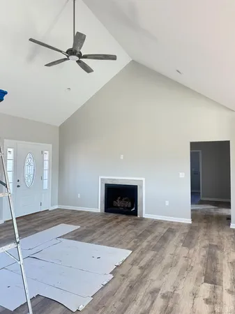 a view of an empty room with a fireplace and a ceiling fan