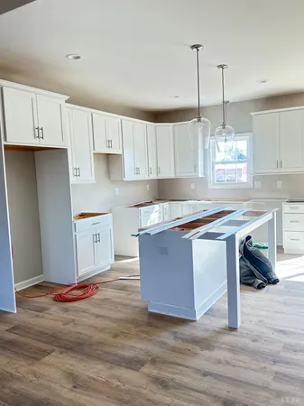 a kitchen with kitchen island granite countertop a stove a sink and white cabinets