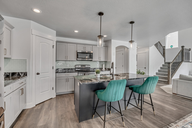 1577 Quailhill Road Saratoga Springs, UT 84045 - Photo 14 of 46 Kitchen featuring a breakfast bar, arched walkways, dark stone countertops, gray cabinetry, and stainless steel appliances