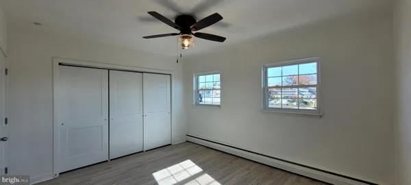 an empty room with windows and fan