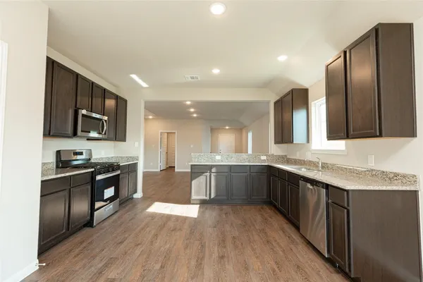 a large kitchen with granite countertop lots of counter top space and stainless steel appliances