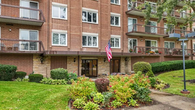 a front view of a brick building with many windows and garden