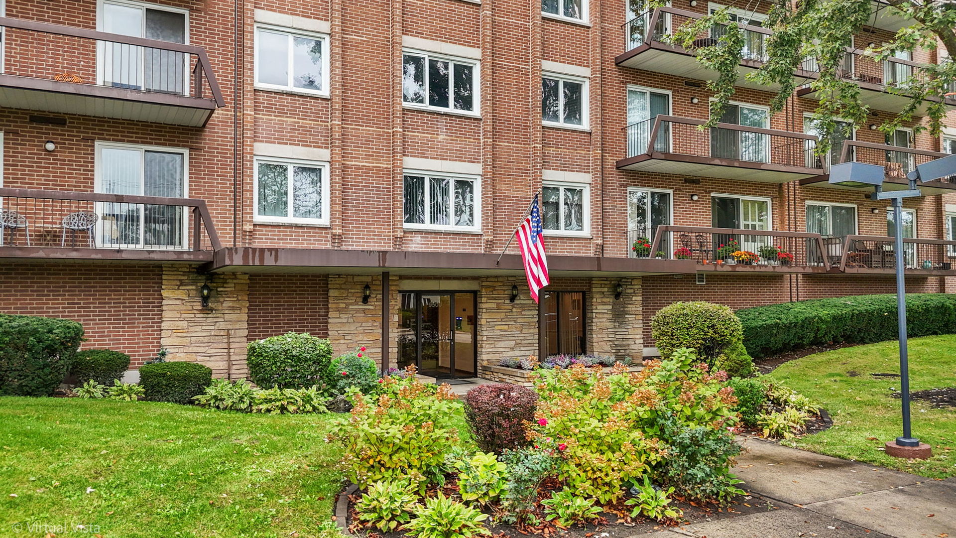 a front view of a brick building with many windows and garden