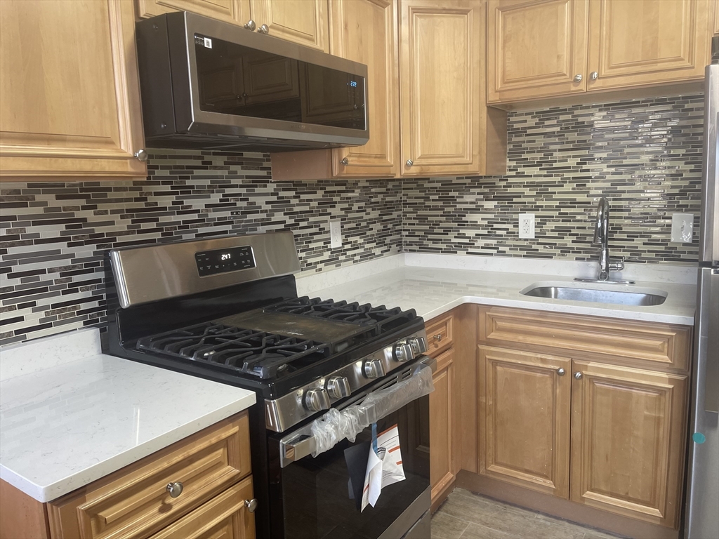 1002 River Street, Unit 2 Boston, MA 02136 - Photo 2 of 12 a kitchen with granite countertop a stove sink and cabinets