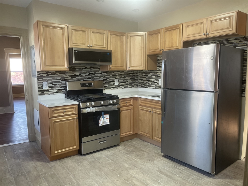 1002 River Street, Unit 2 Boston, MA 02136 - Photo 3 of 12 a kitchen with refrigerator a microwave a sink and cabinets