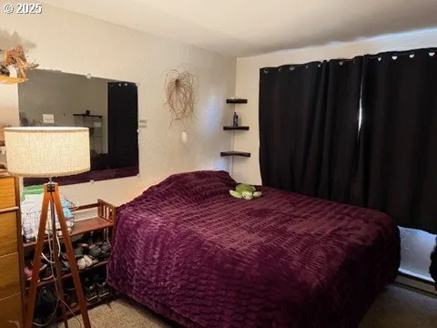 a bedroom with a bed and a flat tv screen on dresser