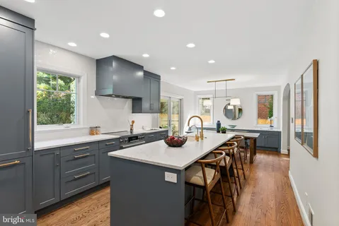 a kitchen with stainless steel appliances granite countertop a table chairs sink and cabinets