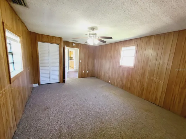 an empty room with windows and fan