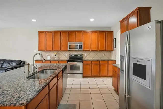 a kitchen with stainless steel appliances granite countertop a refrigerator stove and sink