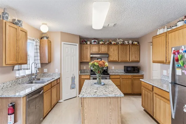 a kitchen with stainless steel appliances granite countertop a sink stove and refrigerator