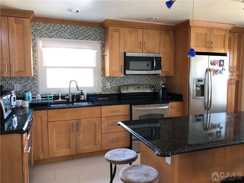 36 Partch Place Edison, NJ 08817 - Photo 22 of 24 a kitchen with stainless steel appliances granite countertop a sink a stove a microwave a refrigerator a counter space and cabinets