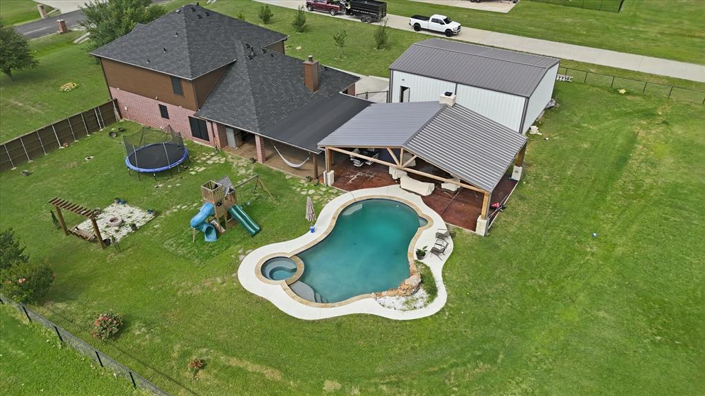 430 Ridgecrest Place Sanger, TX 76266 - Photo 39 of 40 Expansive backyard featuring a freeform swimming pool with integrated spa, a large covered patio structure, and a substantial detached metal building