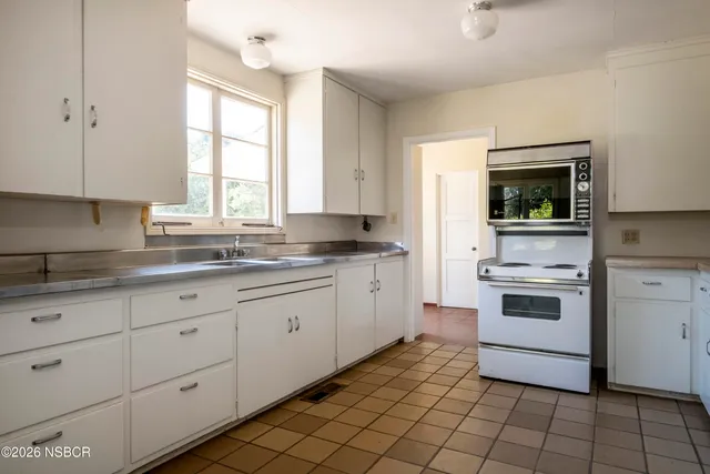 a kitchen with granite countertop white cabinets and appliances