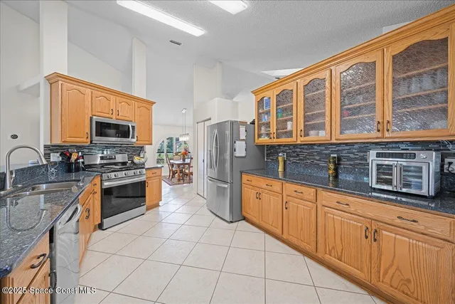a large kitchen with stainless steel appliances granite countertop a stove top oven a sink dishwasher a dining table and chairs with wooden floor