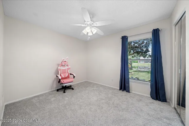 a room with a chandelier fan and a window