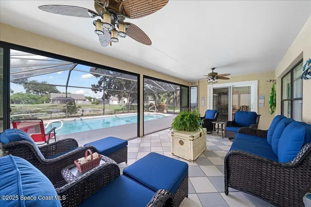 a living room with furniture large windows and wooden floor