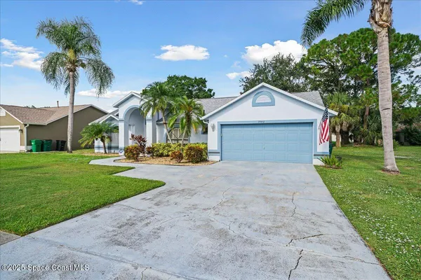 a front view of a house with a garden and palm trees