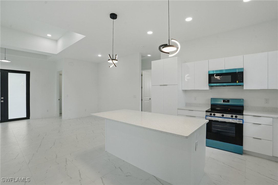 472 Rajah Street Lehigh Acres, FL 33974 - Photo 13 of 29 a large kitchen with cabinets and stainless steel appliances