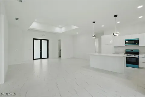 a large white kitchen with kitchen island a sink stainless steel appliances and cabinets