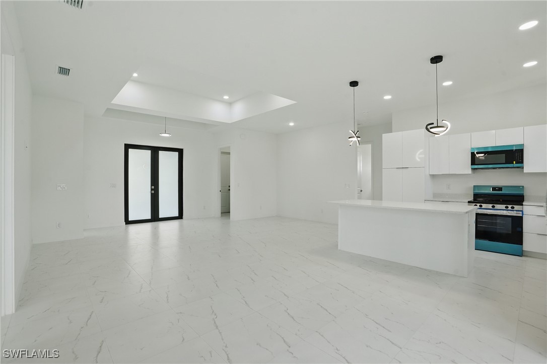 472 Rajah Street Lehigh Acres, FL 33974 - Photo 4 of 29 a large white kitchen with kitchen island a sink stainless steel appliances and cabinets