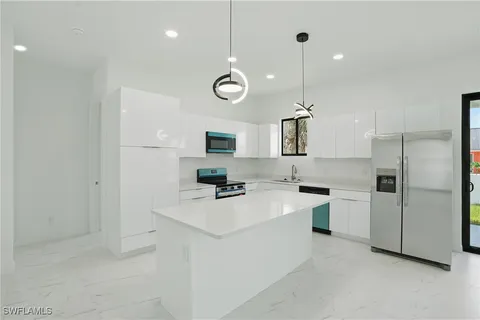 a kitchen with a refrigerator a sink and chandelier