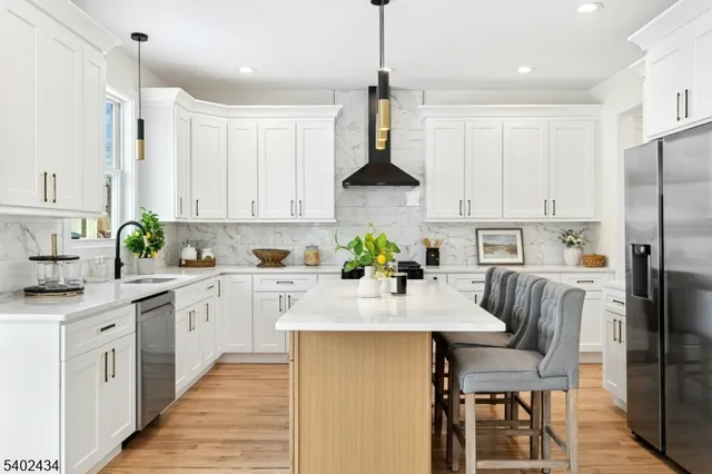 a kitchen with stainless steel appliances kitchen island granite countertop a table chairs refrigerator and sink