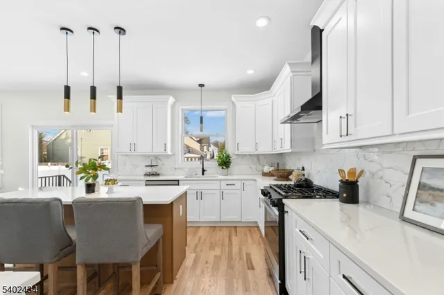 a kitchen with a stove a sink a kitchen island with a cabinets and wooden floor